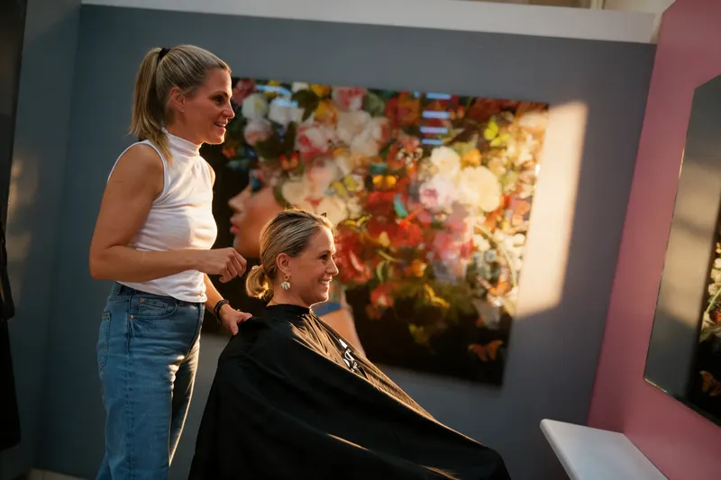 Friseurin im Gespräch mit einer Kundin vor dem Spiegel