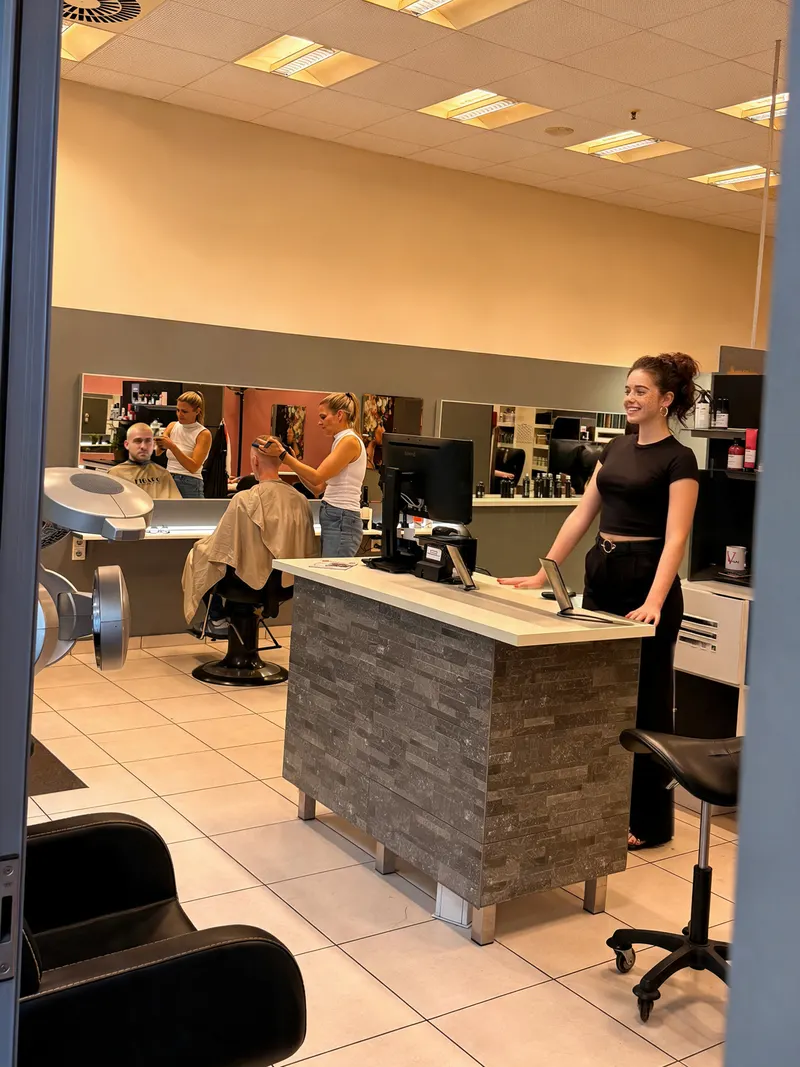 Blick in den Salon mit Empfangstheke und Kolleginnen bei der Arbeit